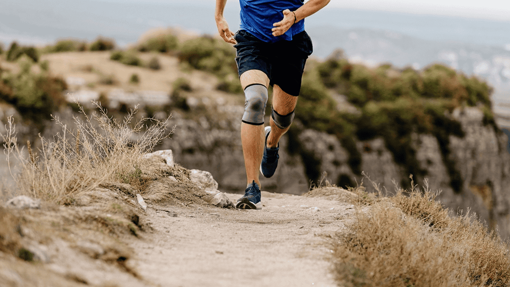 Man running with knee brace on knee in the desert